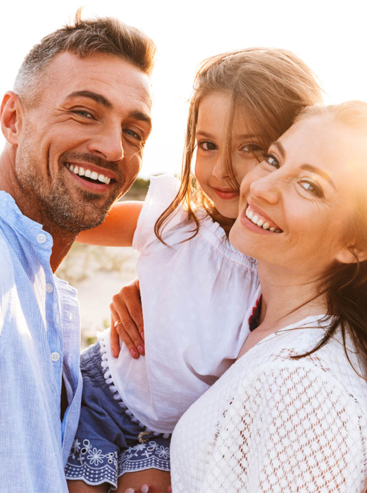 Man, woman, and child outdoors, with the child being held between the adults - https://krupainsurance.com